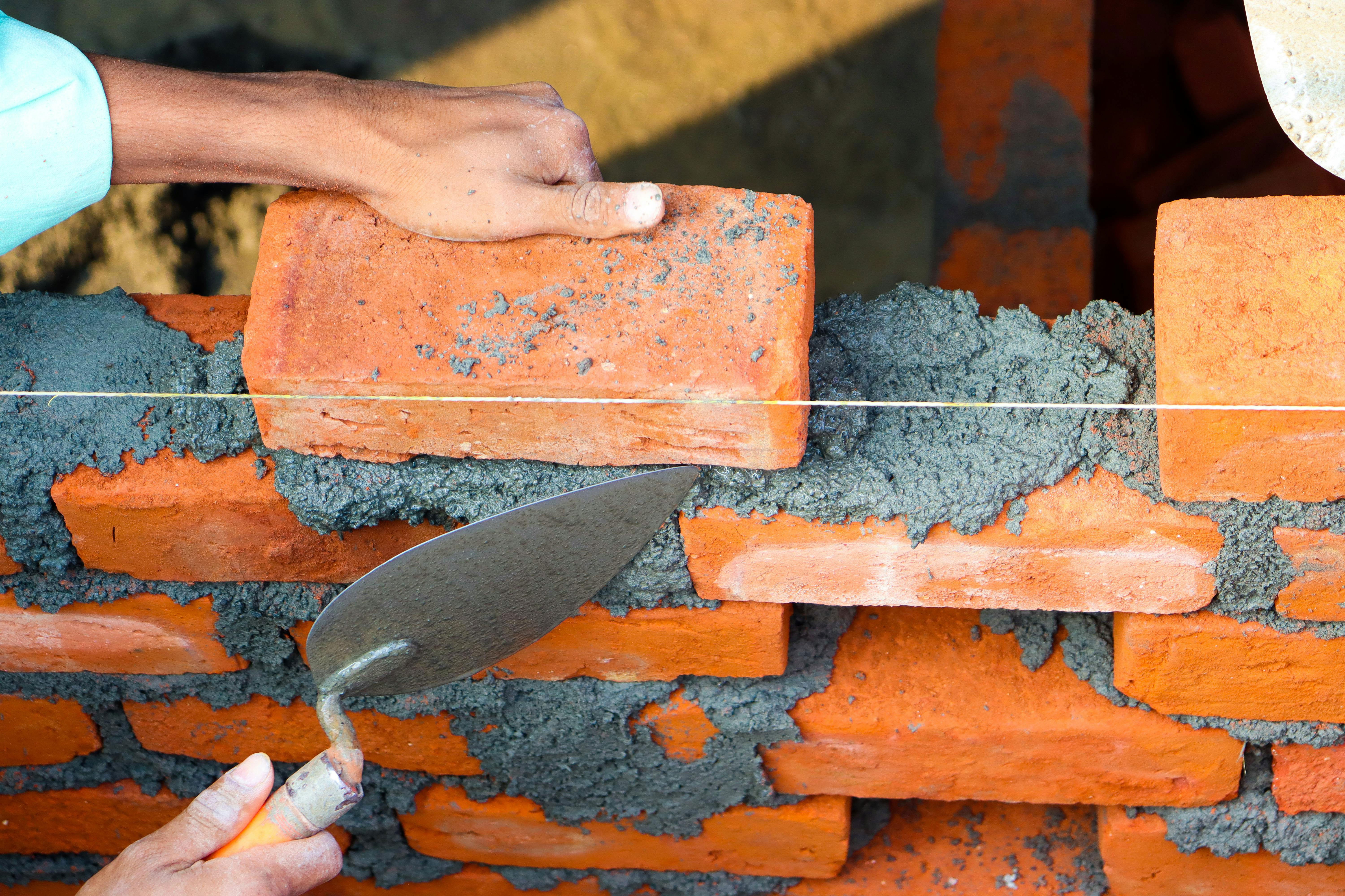 Construction worker installing concrete masonry units (CMU blocks) on an industrial building site.