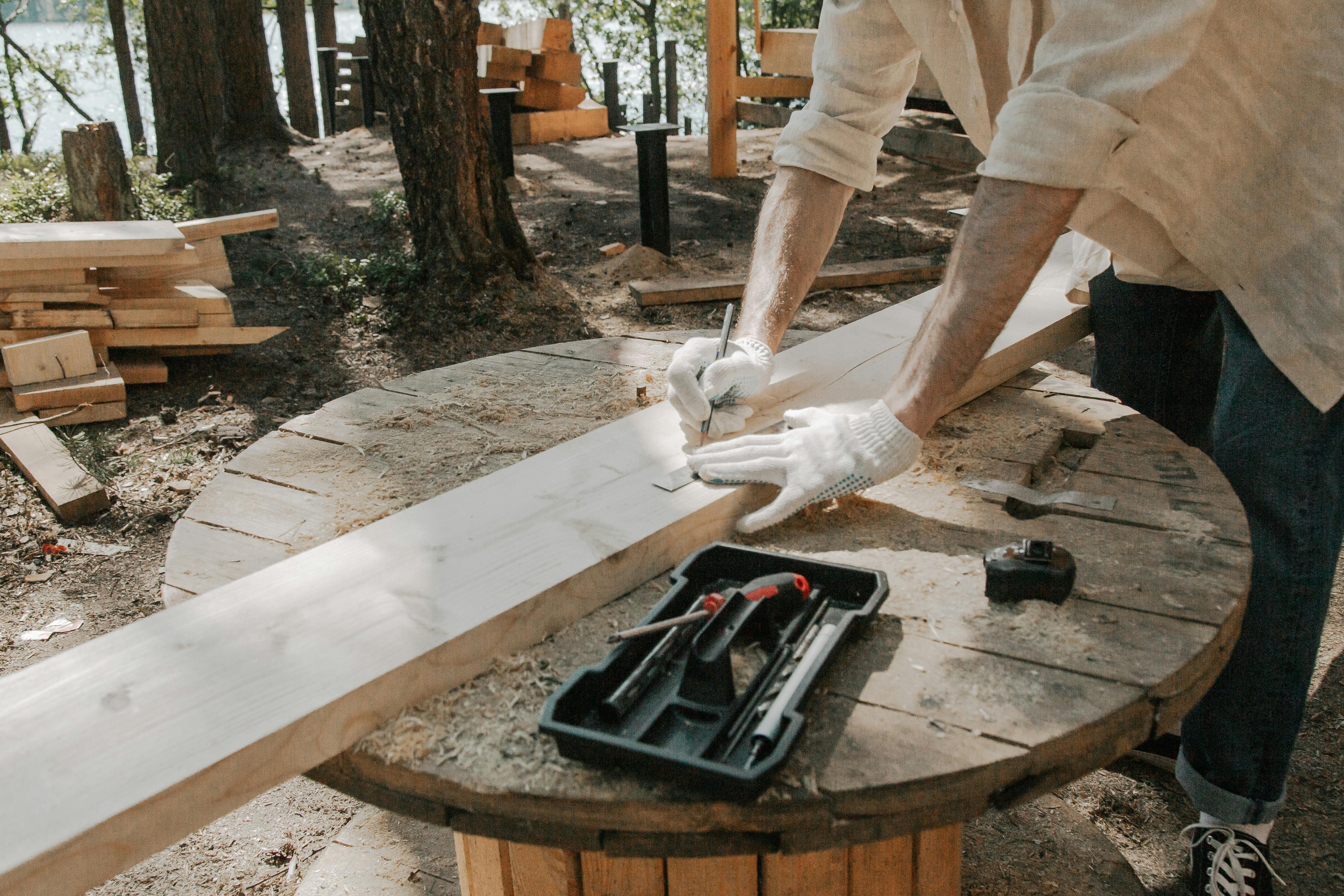 Carpenter measuring and marking wooden elements as part of preparation for doors or structural components.