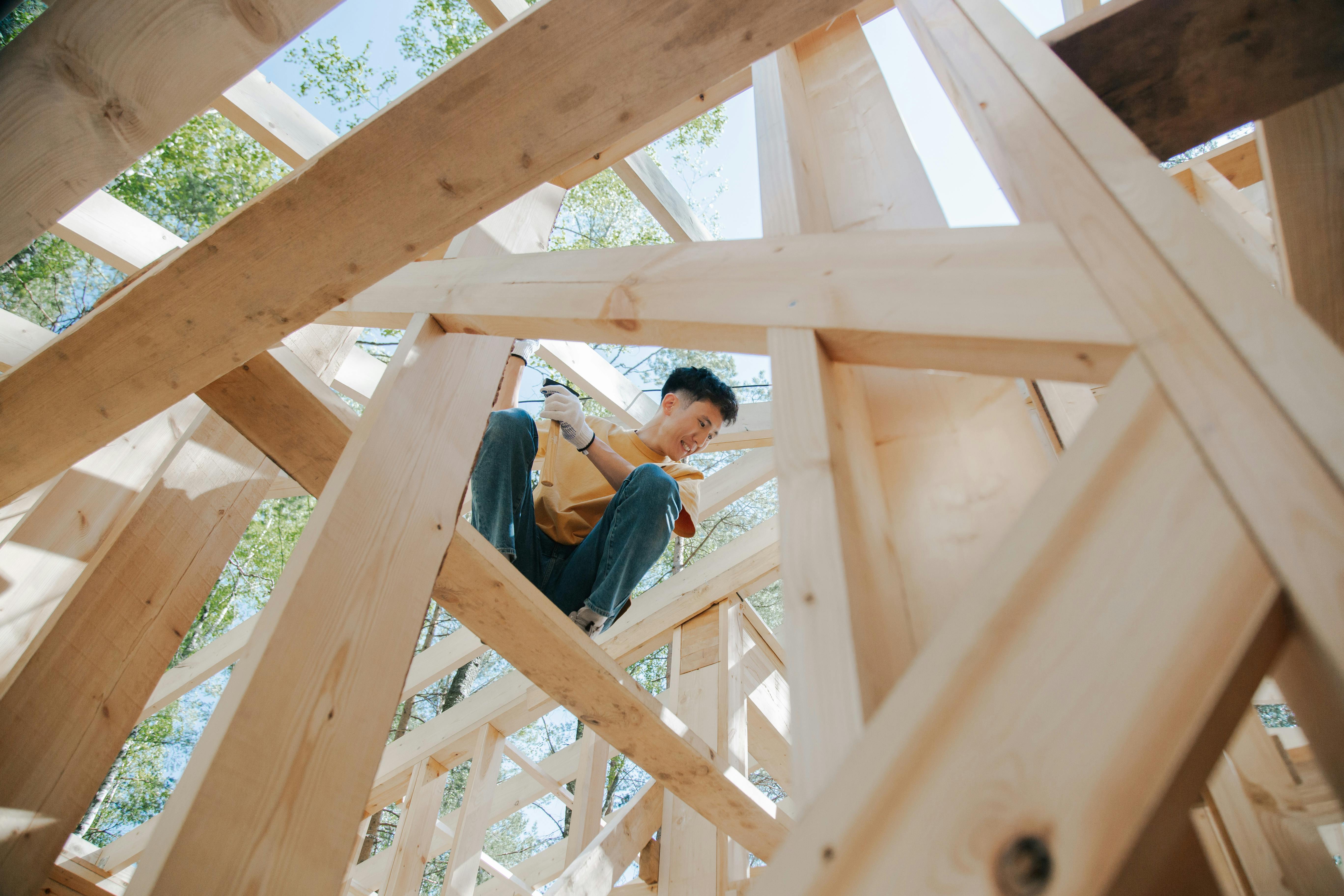 Rough carpenter installing and adjusting structural timber elements inside a wooden framework.