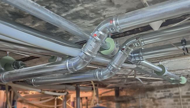 Compact manifold of copper and steel pipes with shut-off valves and fittings for a heating or plumbing system.