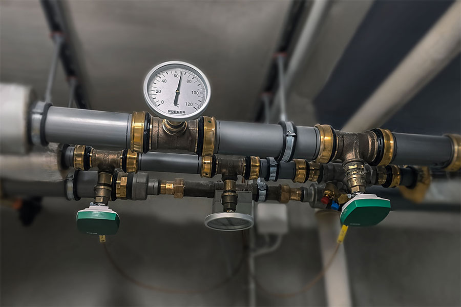 Complex network of heating pipes, elbows and valves forming a distribution manifold in a plant room.