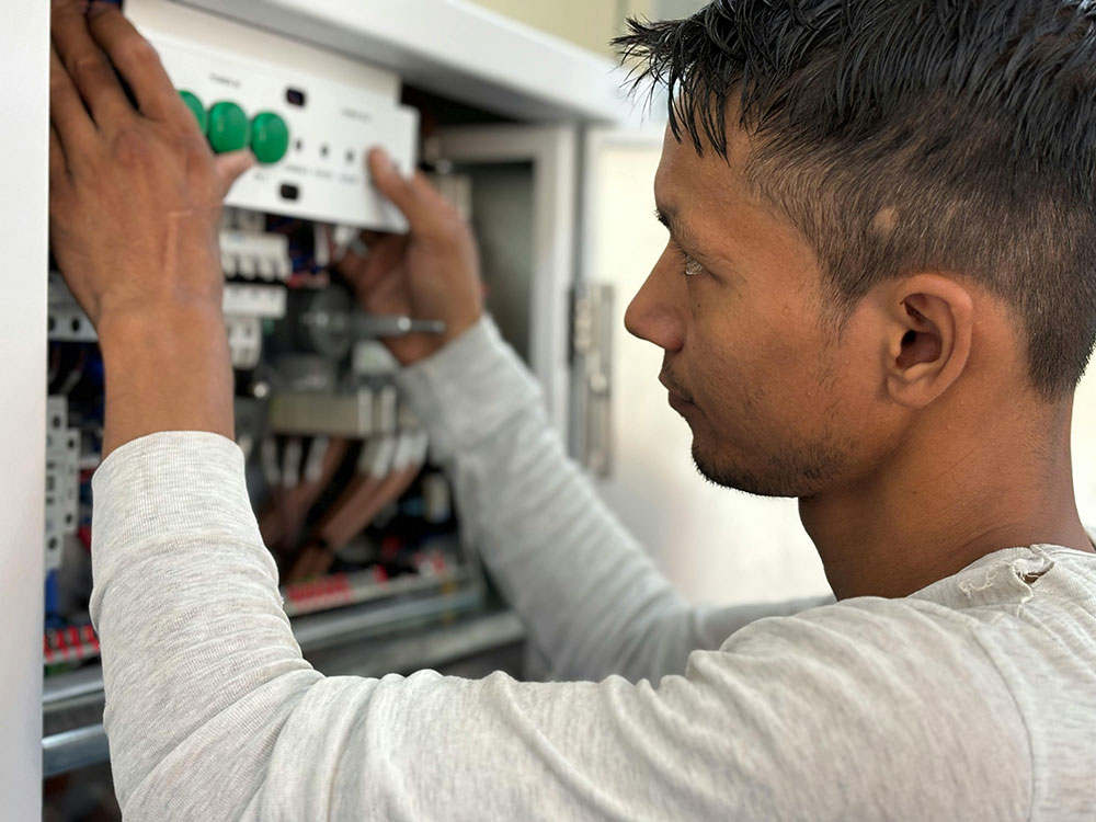 Electrician installing and adjusting electrical control components inside distribution cabinet