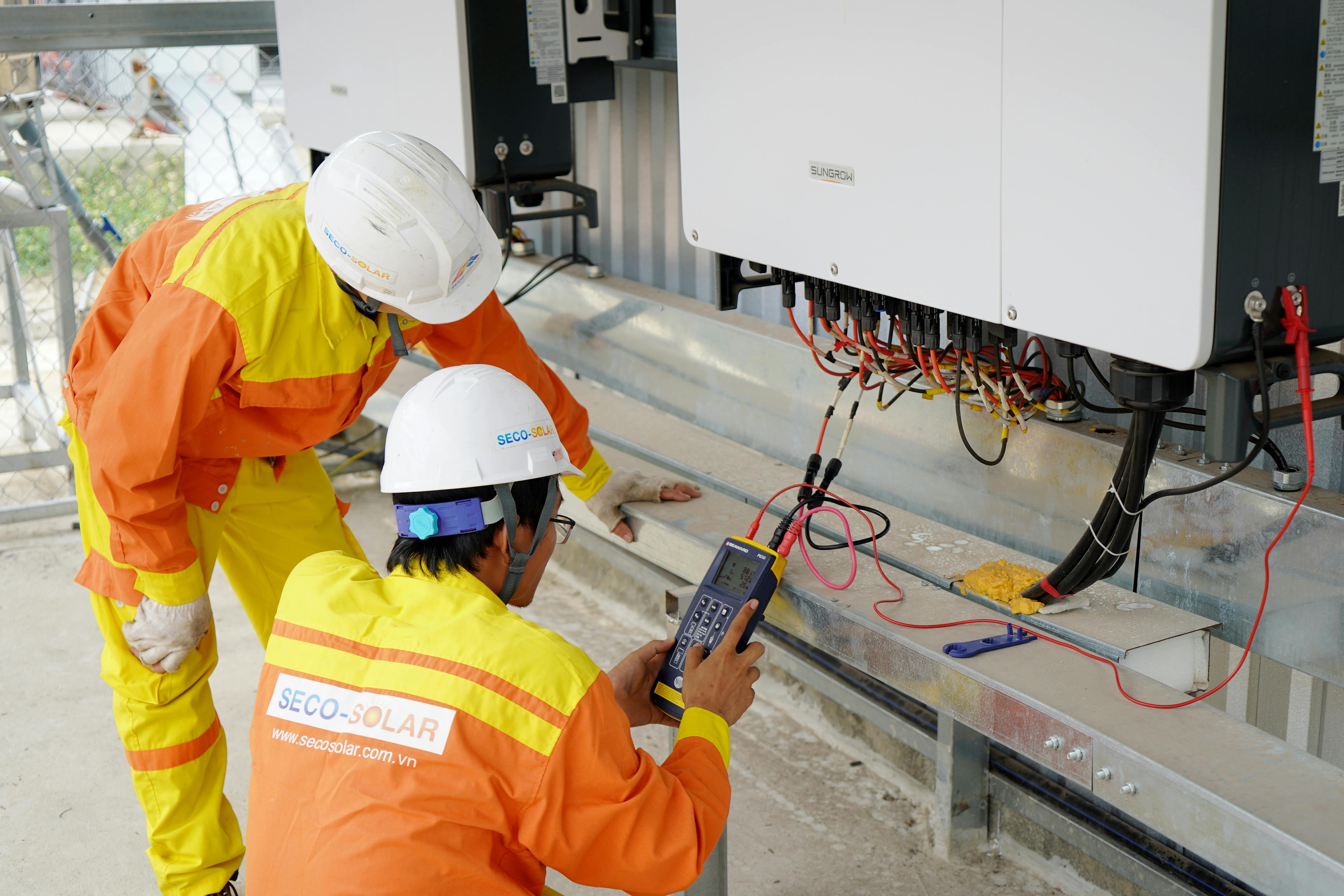 Electricians testing and commissioning electrical connections on industrial power system