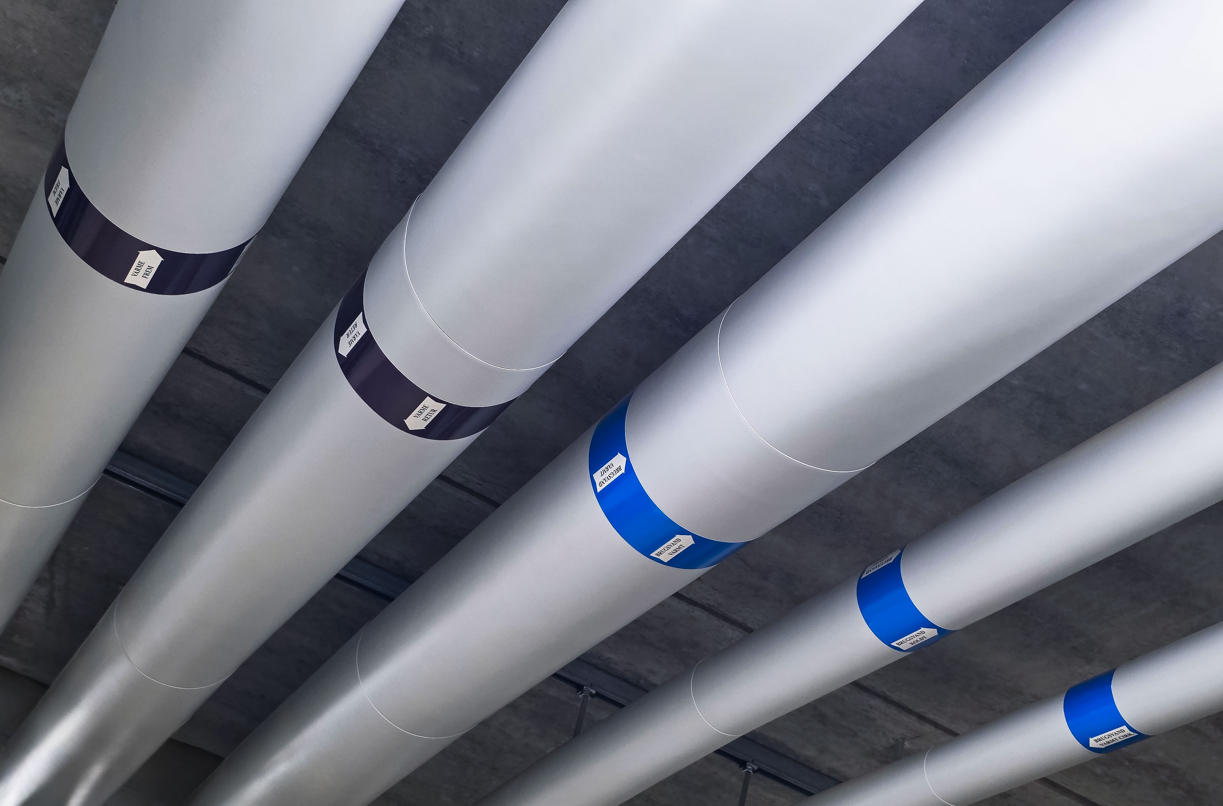 Isogen-clad plumbing pipes with Isover insulation, showing clean joints and durable surface finish in technical installation zone.