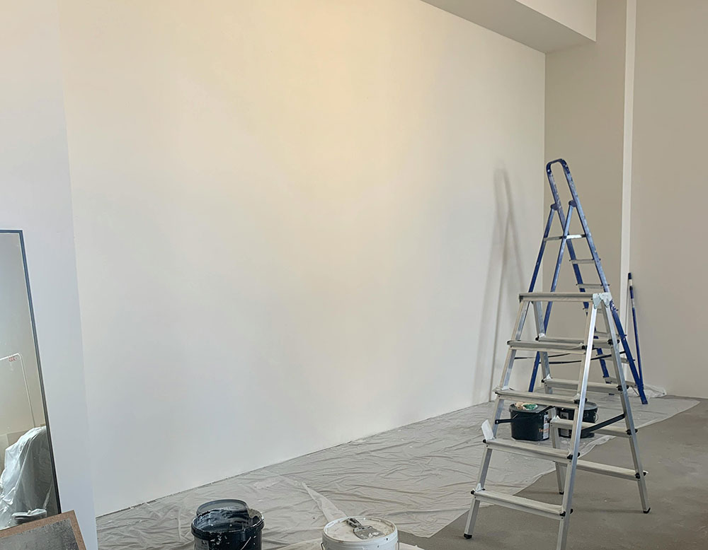 Interior wall prepared for painting with protective floor covering and tools on site