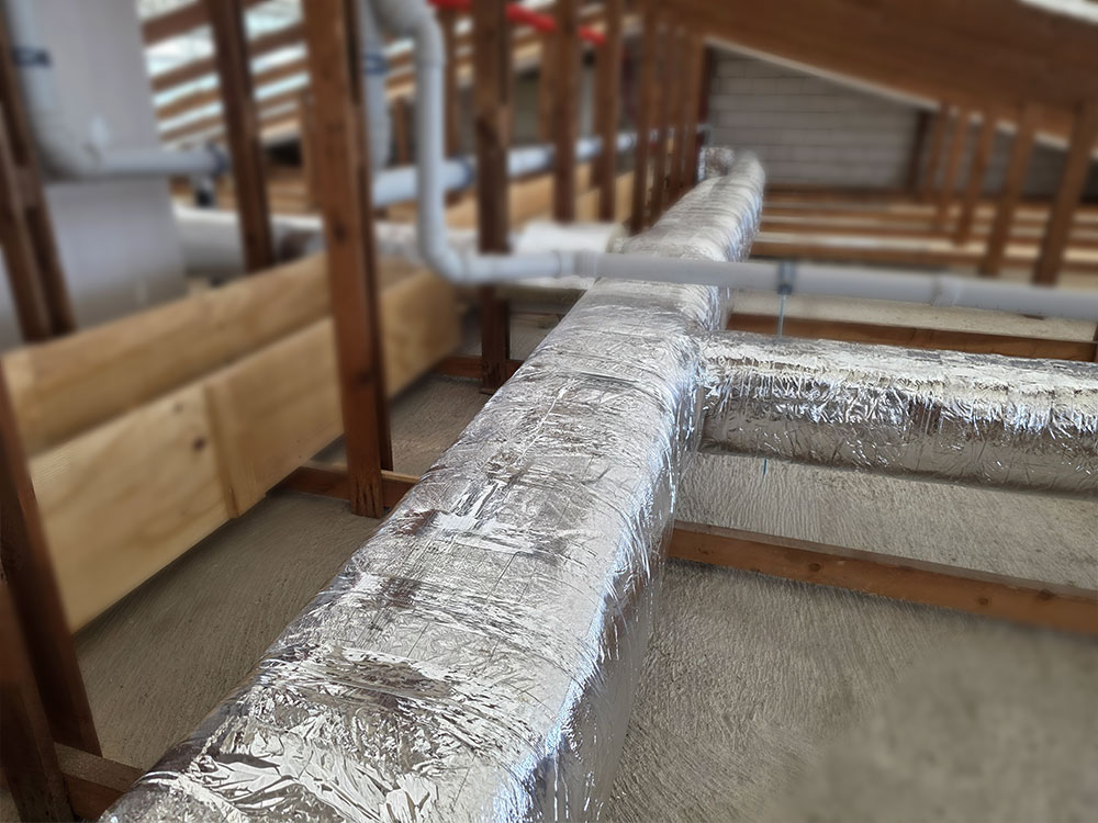 Lamella-insulated ventilation pipes installed in a building ceiling, designed to reduce heat loss and prevent condensation.