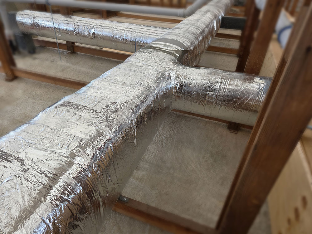 Ventilation duct insulated with lamella mineral wool mats, providing thermal insulation and condensation protection in commercial building installations.