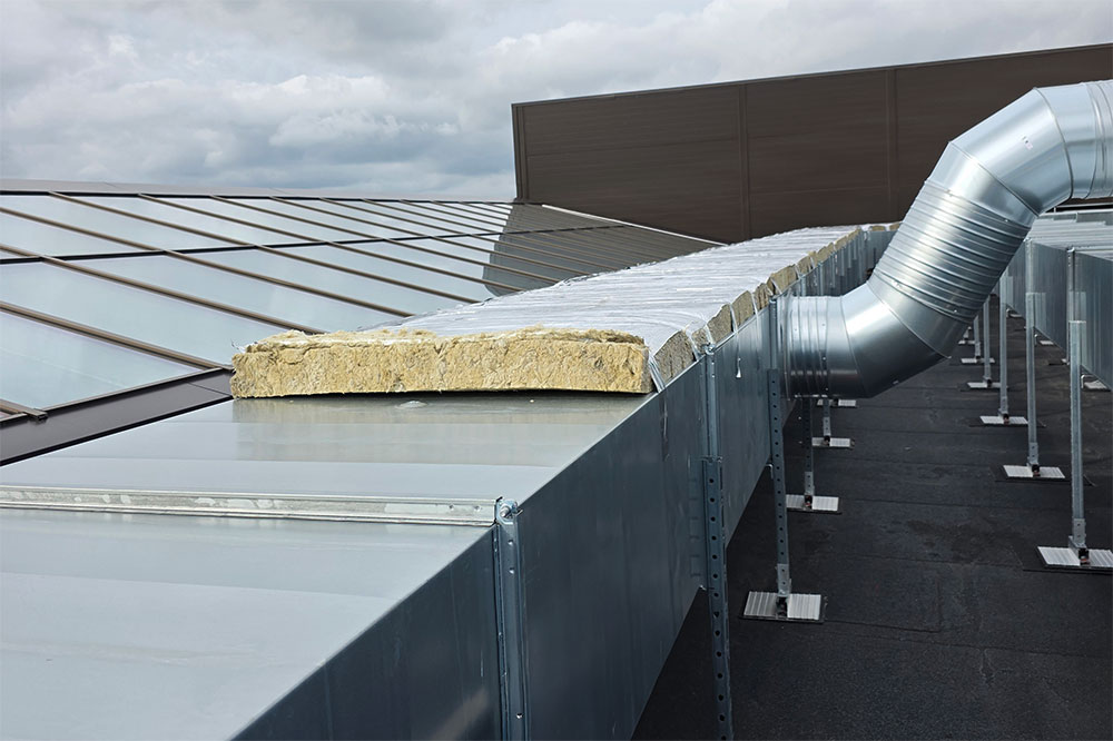 Ventilation ducts with thermal insulation installed on rooftop HVAC systems.