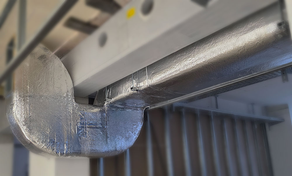 HVAC ventilation pipes insulated with foil-faced lamella mineral wool for energy efficiency and moisture control in technical installations.