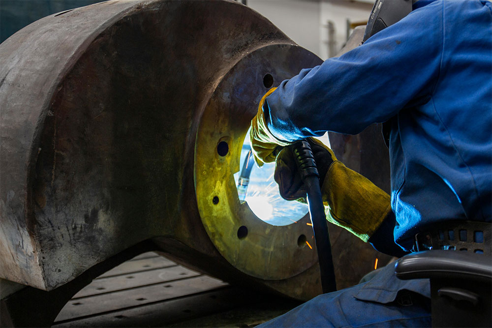 Welder welding a large steel component during industrial fabrication