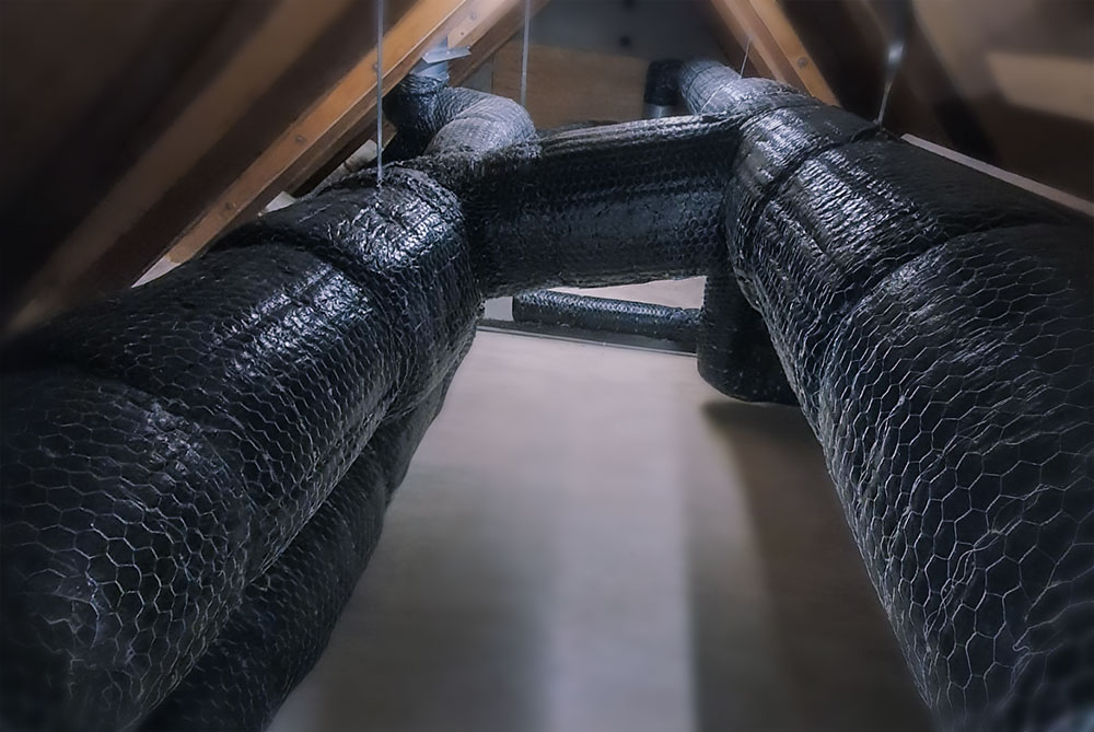 Ventilation ducts wrapped with fire-rated wire mat, fixed and sealed around bends and joints.
