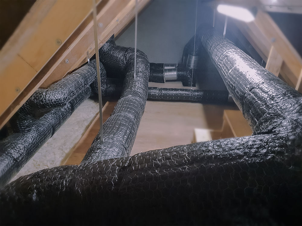 Wire mat fire insulation installed on round HVAC ducts, providing full coverage and mechanical protection.